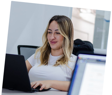 Team member smiling while working on a laptop